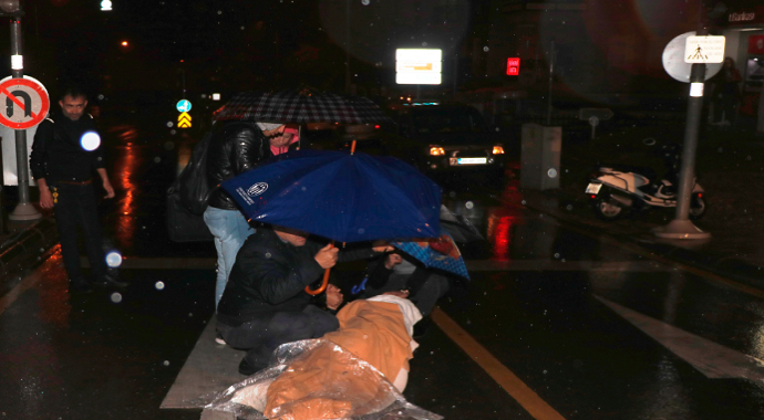 Motosikletten düşen kadını şemsiyelerle yağmurdan korudular