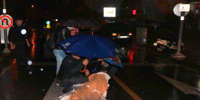Motosikletten düşen kadını şemsiyelerle yağmurdan korudular